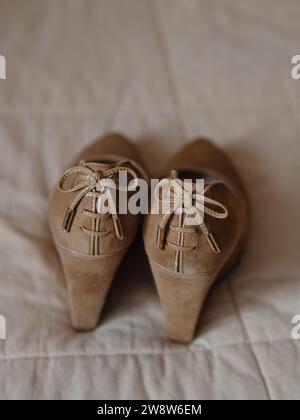 Vertikale Nahaufnahme von beigefarbenen Damenschuhen auf einer soliden, hohen Plattform aus echtem Leder (Wildleder). Auf der Rückseite befinden sich Spitzenschleifen. Ansicht vom Stockfoto