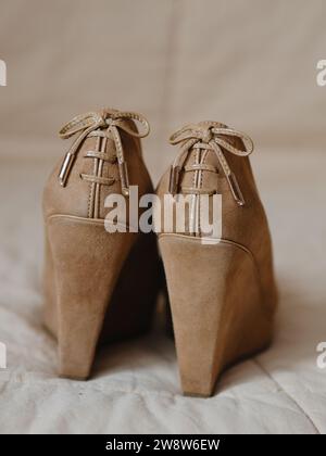 Vertikale Nahaufnahme von beigefarbenen Damenschuhen auf einer soliden, hohen Plattform aus echtem Leder (Wildleder). Auf der Rückseite befinden sich Spitzenschleifen. Ansicht vom Stockfoto