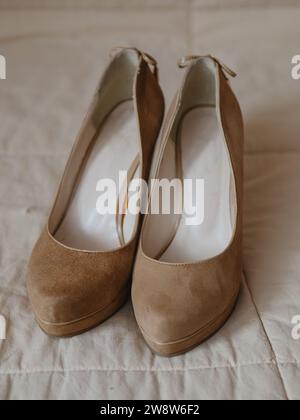 Vertikale Nahaufnahme von beigefarbenen Damenschuhen auf einer soliden, hohen Plattform aus echtem Leder (Wildleder). Auf der Rückseite befinden sich Spitzenschleifen. Ansicht vom Stockfoto