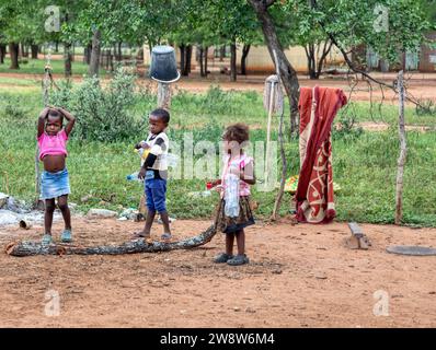 afrikanische Kinder im Dorf sammeln Plastikflaschen auf einer Feldstraße Stockfoto