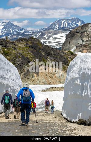 Wanderer navigieren durch die markanten Schneewände am Whistler Mountain, umgeben von den beeindruckenden Ausblicken auf die Kanadischen Rocky Mountains. Stockfoto