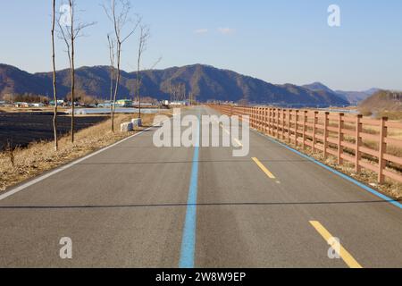 Yeoju City, Südkorea - 20. Februar 2020: Abendsonne taucht die Berge auf und beleuchtet den Hangang Bike Path mit separaten Fahrbahnen für Fahrräder A Stockfoto