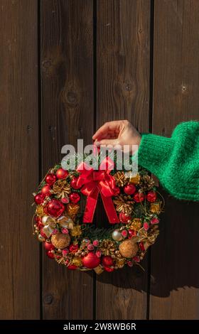 Frauen Hand in grünem Pullover, hängend Tannenkranz für den Advent. Heiligabend und Dekoration. Neujahrsfeier. Stockfoto