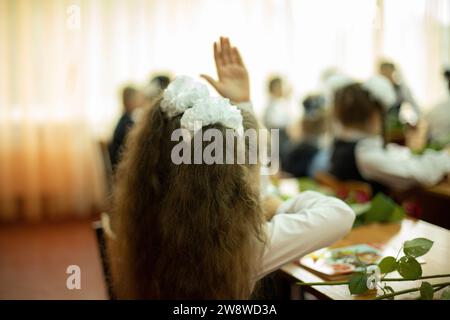 Kind in der ersten Schulstunde. Der Erstklässler zieht seine Hand. Details der Lektion. Der Schüler hob die Hand. Der Schüler fragt den Lehrer. Stockfoto