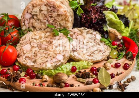 Hausgemachter Kopfkäse auf einem runden Schneidebrett mit Tomaten, Petersilie, Johannisbeeren und anderen Gewürzen und Gemüse Stockfoto