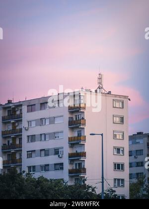 Typischer alter Plattenwohnblock mit vielen Fenstern in Budapest, Ungarn, Mietpreise für Wohnkrisen aus der kommunistischen Zeit, Sonnenuntergang Stockfoto