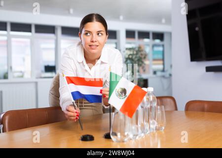 Die junge Dame setzt Miniaturflaggen von Mexiko und den Niederlanden für internationale Verhandlungen Stockfoto