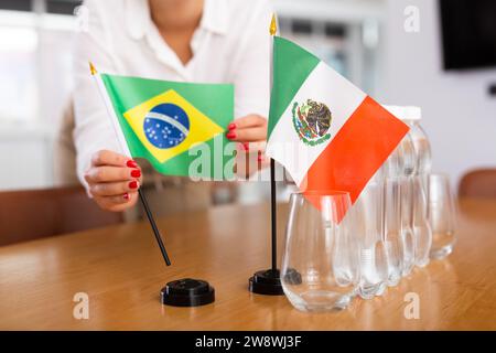 Das unerkennbare Mädchen setzt Zwergflaggen von Mexiko und Brasilien vor internationalen Verhandlungen Stockfoto