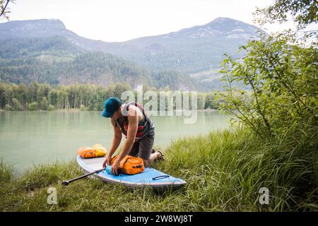 Der SUP Paddle Boarder sichert trockene Taschen und Ausrüstung vor dem Paddeln. Stockfoto