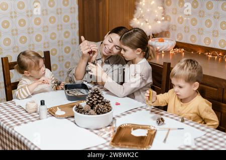 Mama und Kinder machen weihnachtsbasteln aus Tannenzapfen Stockfoto