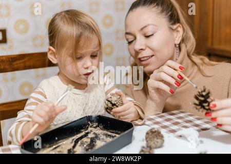 Mom und Tochter machen weihnachtsdekorationen aus Tannenzapfen Stockfoto