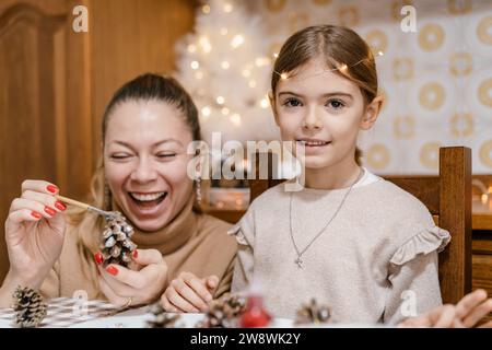 Mom und Tochter machen weihnachtsdekorationen aus Tannenzapfen Stockfoto