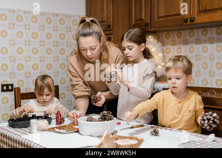 Mama und Kinder machen weihnachtsbasteln aus Tannenzapfen Stockfoto