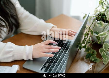 Frau, die an ihrem Laptop arbeitet, an ihrem Schreibtisch zu Hause Stockfoto