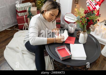 Eine Frau, die ihre weihnachtskarten ausschreibt und Post schickt Stockfoto