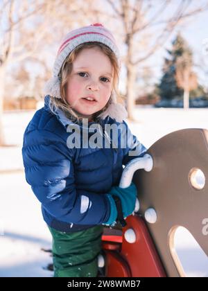 Lächelndes Mädchen in warmer Winterkleidung auf einem Spielplatz Stockfoto