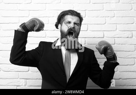 Verrückter Mann beim Boxen. Lustig aufgeregt Boxer Geschäftsmann. Junger Mann im Anzug und Boxhandschuhen, Geschäftsgewinnerin. Wütend lustig bärtigen Geschäftsmann. Stockfoto