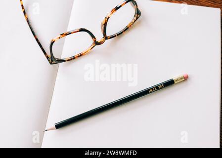 Brille auf einem offenen Buch mit Bleistift Stockfoto