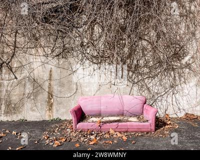 Altes pinkfarbenes Sofa auf leerem Grundstück im Freien Stockfoto