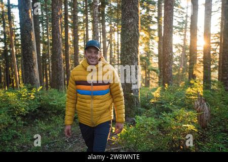 Mann, der durch den Wald wandert, in warmer Winterjacke Stockfoto