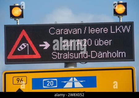 22. Dezember 2023, Mecklenburg-Vorpommern, Altefähr: Wegen des stürmischen Wetters sollten leere LKW und Wohnwagen die Rügenbrücke zwischen Stralsund und Rügen nicht überqueren. Stattdessen sollten sie über den unteren Rügendamm fahren. Elektronische Anzeigen vor der Zufahrtsstraße wiesen die Fahrer am Freitagnachmittag an, geeignete Ausweichmaßnahmen zu ergreifen. Der Deutsche Wetterdienst warnte bis Freitag vor Sturmwinden – vor allem an der Küste westlich von Rostock bis Vorpommern. Foto: Stefan sauer/dpa Stockfoto