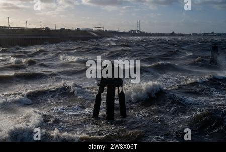 22. Dezember 2023, Mecklenburg-Vorpommern, Altefähr: Wellen brechen am Strand von Altefähr auf der Insel Rügen. Im Hintergrund ist die Silhouette der Hansestadt Stralsund zu sehen. Der Deutsche Wetterdienst warnte bis Freitag vor Sturmwinden – vor allem an der Küste westlich von Rostock bis Vorpommern. Foto: Stefan sauer/dpa Stockfoto