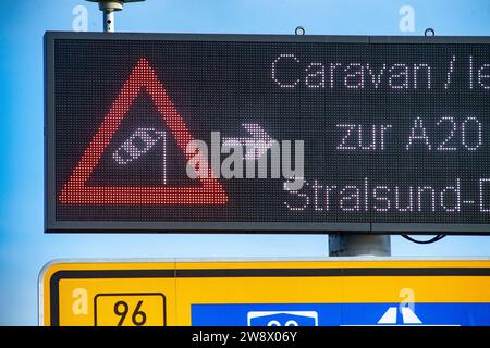 22. Dezember 2023, Mecklenburg-Vorpommern, Altefähr: Wegen des stürmischen Wetters sollten leere LKW und Wohnwagen die Rügenbrücke zwischen Stralsund und Rügen nicht überqueren. Stattdessen sollten sie über den unteren Rügendamm fahren. Elektronische Anzeigen vor der Zufahrtsstraße wiesen die Fahrer am Freitagnachmittag an, geeignete Ausweichmaßnahmen zu ergreifen. Der Deutsche Wetterdienst warnte bis Freitag vor Sturmwinden – vor allem an der Küste westlich von Rostock bis Vorpommern. Foto: Stefan sauer/dpa Stockfoto