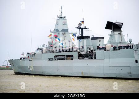 Wilhelmshaven, Deutschland. Dezember 2023. Besatzungsmitglieder mit Weihnachtsmützen stehen an Bord der Fregatte „Hessen“, während das Schiff in den Hafen am Marinestützpunkt einfährt. Mit rund 230 Soldaten und Frauen an Bord kehrte die Fregatte kurz vor Weihnachten in ihren Heimathafen zurück. In den letzten fünf Monaten hatte das Schiff an drei großen Manövern und zahlreichen Übungen in der Nord-, Ostsee- und Nordatlantik teilgenommen. Quelle: Hauke-Christian Dittrich/dpa/Alamy Live News Stockfoto