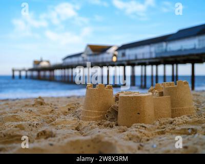 Southwold, Suffolk, England - die Überreste einer Sandburg am Strand neben dem berühmten Wahrzeichen von Suffolk am Southwold Pier. Stockfoto