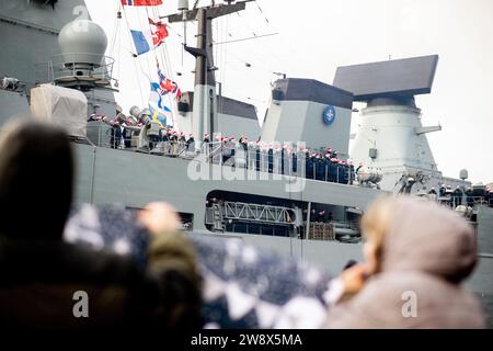 Wilhelmshaven, Deutschland. Dezember 2023. Besatzungsmitglieder mit Weihnachtsmützen winken von an Bord der Fregatte „Hessen“, während das Schiff in den Hafen am Marinestützpunkt einfährt. Mit rund 230 Soldaten und Frauen an Bord kehrte die Fregatte kurz vor Weihnachten in ihren Heimathafen zurück. In den letzten fünf Monaten hatte das Schiff an drei großen Manövern und zahlreichen Übungen in der Nord-, Ostsee- und Nordatlantik teilgenommen. Quelle: Hauke-Christian Dittrich/dpa/Alamy Live News Stockfoto