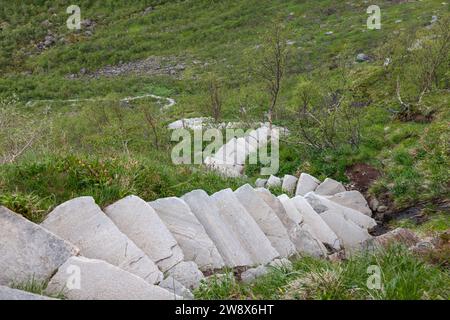 Steintreppe auf einem grünen Hügel, Teil des Reinebringen-Weges in Lofoten, Norwegen, mit einer Mischung aus künstlicher Struktur und natürlicher Landschaft Stockfoto