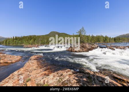 Dynamische Kaskaden des Namsen-Flusses in Namsskogan, Trondelag, Norwegen, mit Fokus auf strukturierten Flusssteinen, durchsetzt mit großen bou Stockfoto