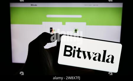 Person mit Handy mit Logo der deutschen Fintech-Firma Bitwala GmbH vor der Business-Website. Schwerpunkt auf dem Display des Telefons. Stockfoto