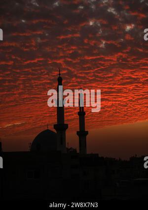 Rafah, Gaza. Dezember 2023. Der Himmel ist rot beleuchtet bei Sonnenuntergang hinter den Minaretten der Moschee in Rafah im südlichen Gazastreifen, am Freitag, den 22. Dezember 2023. Foto: Ismael Mohamad/UPI Credit: UPI/Alamy Live News Stockfoto