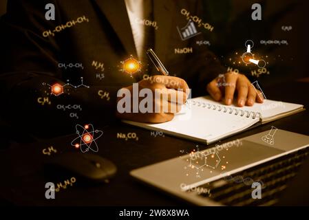 Eine männliche Hand, die einen Stift hält, schreibt wissenschaftliche Daten oder mathematische Formeln am Schreibtisch auf. Stockfoto
