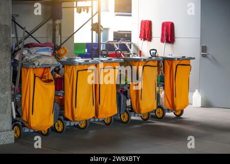 Reinigungswagen mehrere Teile hintereinander an einem öffentlichen Ort mit Reinigungsprodukten: Mopp, Eimer zur Bodenreinigung, Besenlöffel, Haushaltschemikalien, Stockfoto