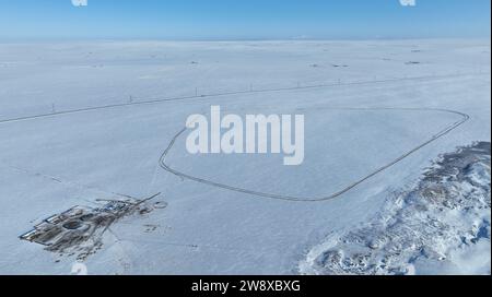 (231222) -- HULUN BUIR, 22. Dezember 2023 (Xinhua) -- dieses Luftbild zeigt Erdendalais Haus und eine Rennstrecke, die er in Hulun Buir, Nordchinas autonomer Region Innere Mongolei, gebaut hat, 16. Dezember 2023. Der Winter bedeutet normalerweise Herausforderungen für Hirten, die auf dem Grasland leben. Starke Kälte und Schnee beeinflussen immer ihr tägliches Leben. Aber für Erdendalai, einen Hirten, der in Hulun Buir lebt, ist der Winter immer noch eine arbeitsreiche Jahreszeit. Neben der Betreuung von mehr als 200 Rindern, Schafen und Pferden, die er besitzt, genießt Erdendalai auch eine wichtige Aktivität des Pferderennens. Pferde waren schon immer ein zuverlässiges Maß Stockfoto