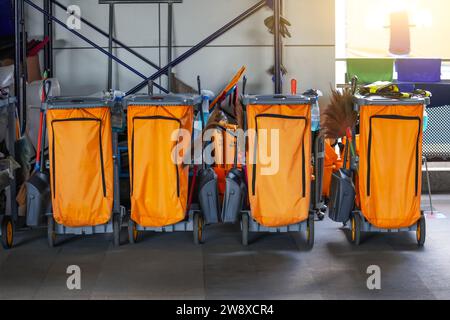 Reinigungswagen mehrere Teile hintereinander an einem öffentlichen Ort mit Reinigungsprodukten: Mopp, Eimer zur Bodenreinigung, Besenlöffel, Haushaltschemikalien, Stockfoto