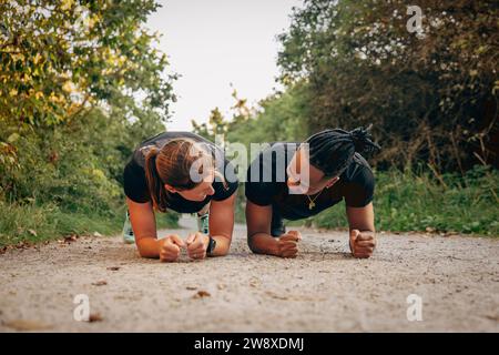 Junger Mann, der Plank-Position mit Frau auf dem Fußweg übt Stockfoto