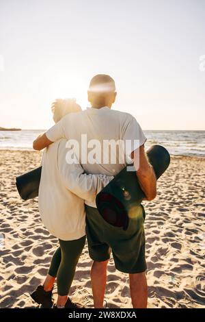 Älteres älteres Ehepaar, das am Strand mit Armen herumsteht Stockfoto