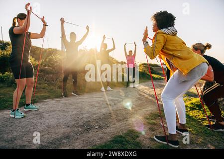 Teamtraining zusammen mit Widerstandsbändern in der Nähe des Fußwegs an sonnigen Tagen Stockfoto