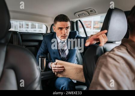 Geschäftsmann, der dem Fahrer hilft, während er im Taxi sitzt Stockfoto