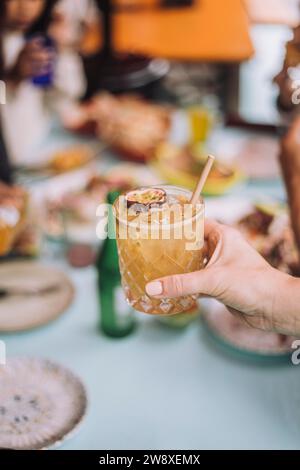 Hand des Mannes mit Cocktailglas, garniert mit Passionsfruchtescheibe im Restaurant Stockfoto