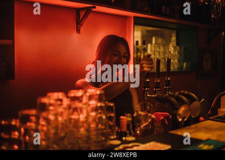 Weibliche Barkeeperin füllte Bier in Glas, während sie an der Bar arbeitete Stockfoto