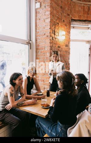 Freundinnen, die miteinander reden, sitzen am Tisch im Café Stockfoto