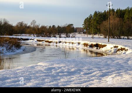 Kleiner, schmaler Fluss im Winter, Flussbiegung, Wasserreflexionen Stockfoto