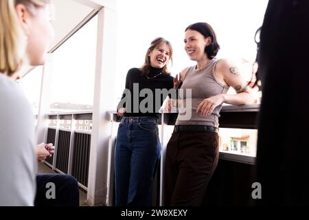 Glückliche junge Freundinnen, die lachen und Spaß auf dem Balkon haben Stockfoto