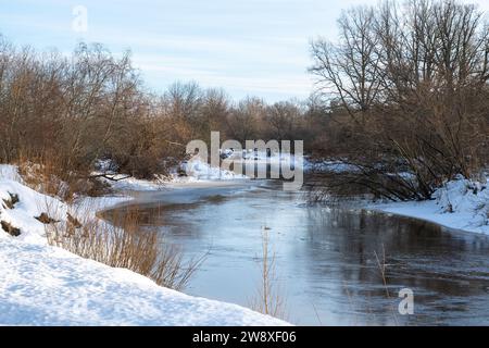 Kleiner, schmaler Fluss im Winter, Flussbiegung, Wasserreflexionen Stockfoto