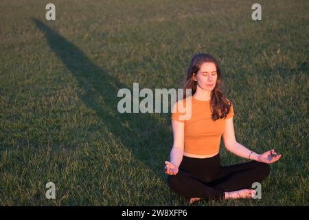 Eine junge weiße Frau, die im Park meditiert Stockfoto