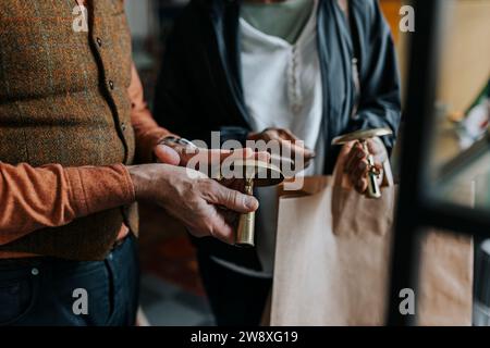 Mittelteil des Verkäufers mit Kerzenhalter, der weibliche Kundin im Geschäft steht Stockfoto